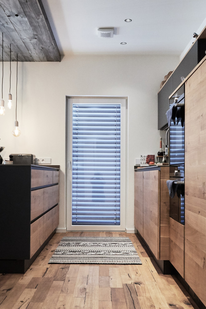 Zweizeilige, Mittelgroße Moderne Wohnküche mit Unterbauwaschbecken, flächenbündigen Schrankfronten, hellbraunen Holzschränken, Kücheninsel und grauer Arbeitsplatte in München