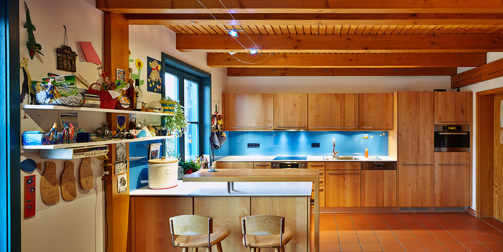 На фото: большая параллельная кухня-гостиная в скандинавском стиле с накладной мойкой, плоскими фасадами, коричневыми фасадами, синим фартуком, фартуком из стекла, полом из терракотовой плитки, островом, стеклянной столешницей и техникой под мебельный фасад