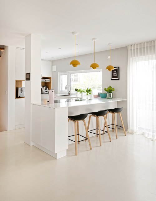 Bright and Inviting: White U-shaped Kitchen with Yellow Pendant Lamps and Black Chairs