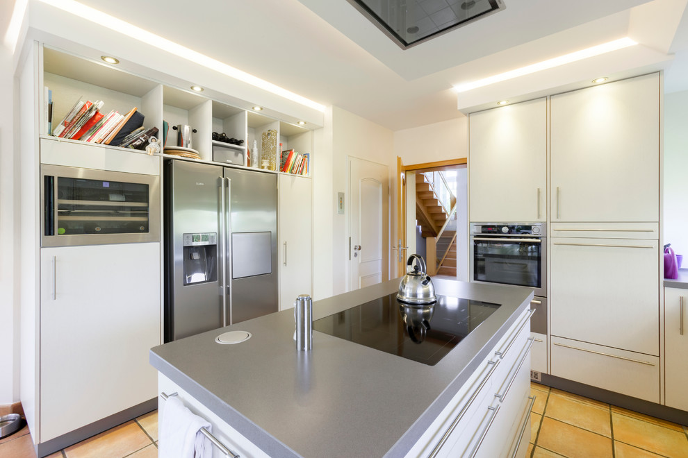 Bild på ett avskilt, stort funkis kök, med släta luckor, vita skåp, bänkskiva i rostfritt stål, rostfria vitvaror och en köksö