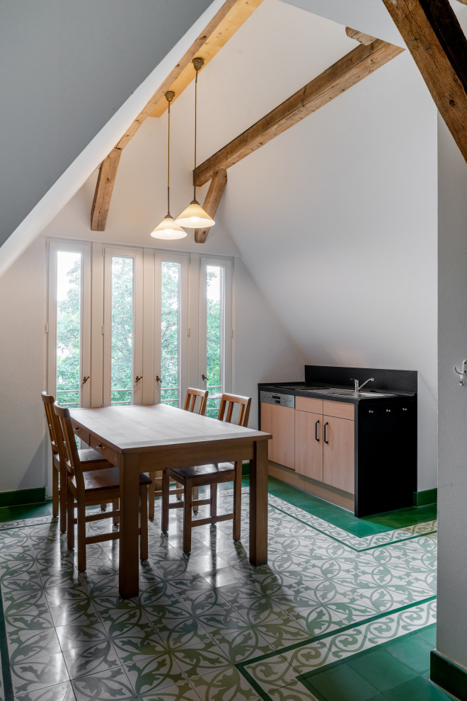 他の地域にある高級な広いカントリー風のおしゃれなキッチン (一体型シンク、フラットパネル扉のキャビネット、淡色木目調キャビネット、人工大理石カウンター、黒いキッチンパネル、スレートのキッチンパネル、シルバーの調理設備、磁器タイルの床、アイランドなし、緑の床、黒いキッチンカウンター) の写真