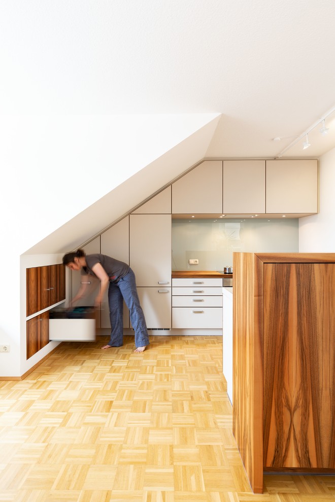 Idéer för att renovera ett mycket stort funkis vit vitt kök, med en integrerad diskho, släta luckor, beige skåp, bänkskiva i koppar, vitt stänkskydd, glaspanel som stänkskydd, integrerade vitvaror, ljust trägolv, en halv köksö och brunt golv