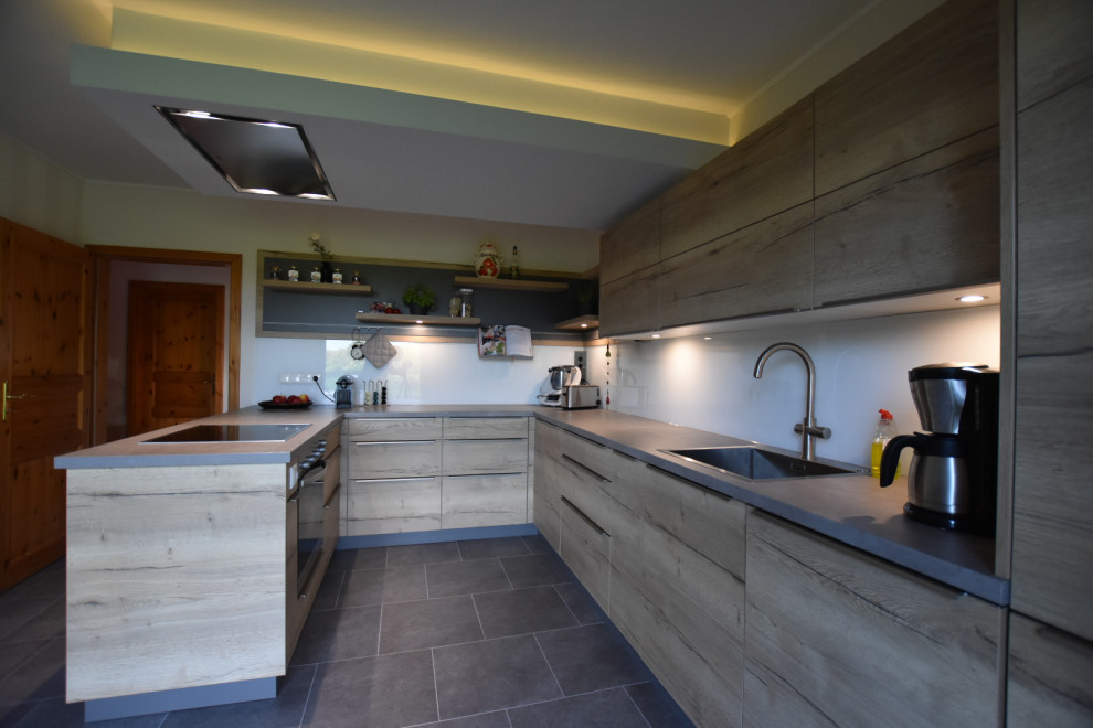 Exempel på ett mellanstort modernt kök, med en enkel diskho, släta luckor, skåp i ljust trä, bänkskiva i betong, vitt stänkskydd, glaspanel som stänkskydd, integrerade vitvaror, vinylgolv, en halv köksö och grått golv