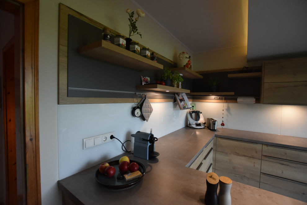 Inspiration for a medium sized contemporary u-shaped open plan kitchen in Hamburg with a single-bowl sink, flat-panel cabinets, light wood cabinets, concrete worktops, white splashback, glass sheet splashback, integrated appliances, vinyl flooring, a breakfast bar and grey floors.