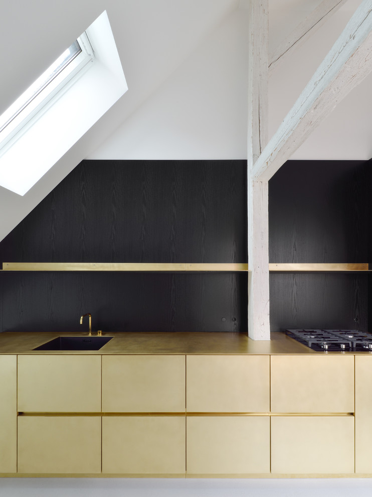 Moderne Küche mit Einbauwaschbecken, flächenbündigen Schrankfronten, Küchenrückwand in Schwarz und Betonboden in München