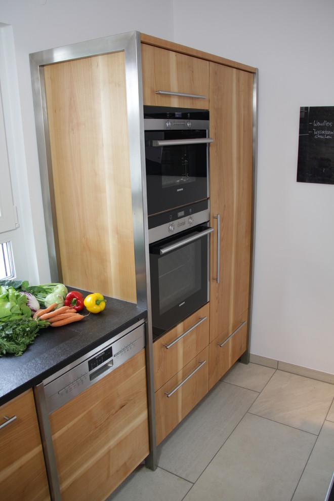 Esempio di una cucina minimal di medie dimensioni con ante lisce, ante in legno chiaro, top in granito, paraspruzzi bianco, paraspruzzi con lastra di vetro, top nero e lavello sottopiano