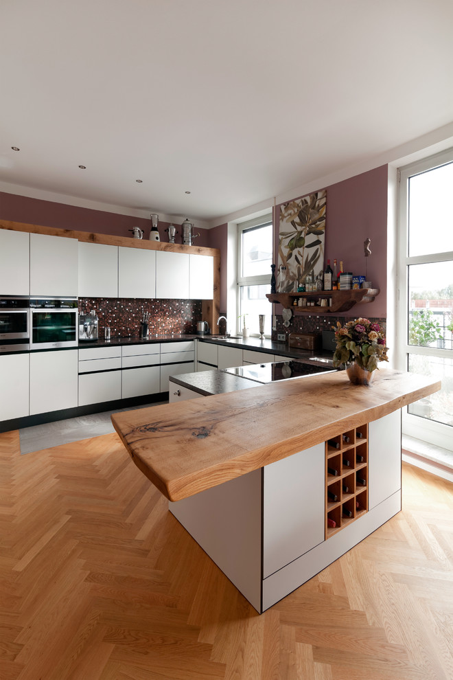 ミュンヘンにある広いトラディショナルスタイルのおしゃれなキッチン (ドロップインシンク、フラットパネル扉のキャビネット、白いキャビネット、木材カウンター、茶色いキッチンパネル、モザイクタイルのキッチンパネル、シルバーの調理設備、無垢フローリング) の写真