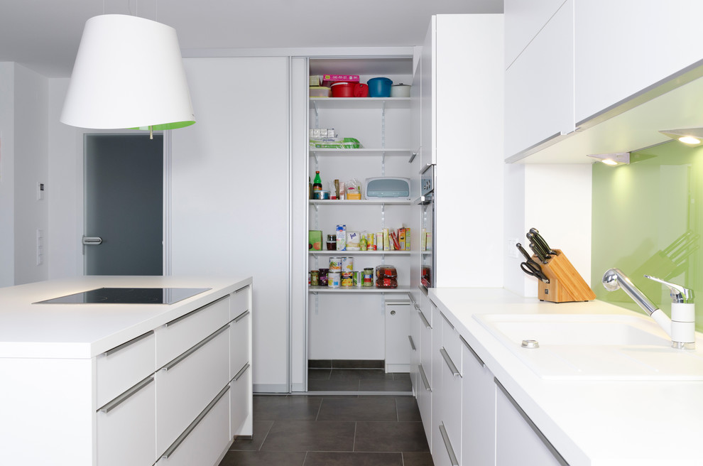 Inspiration for a medium sized contemporary kitchen in Nuremberg with flat-panel cabinets, white cabinets, green splashback, glass sheet splashback, an island and a built-in sink.
