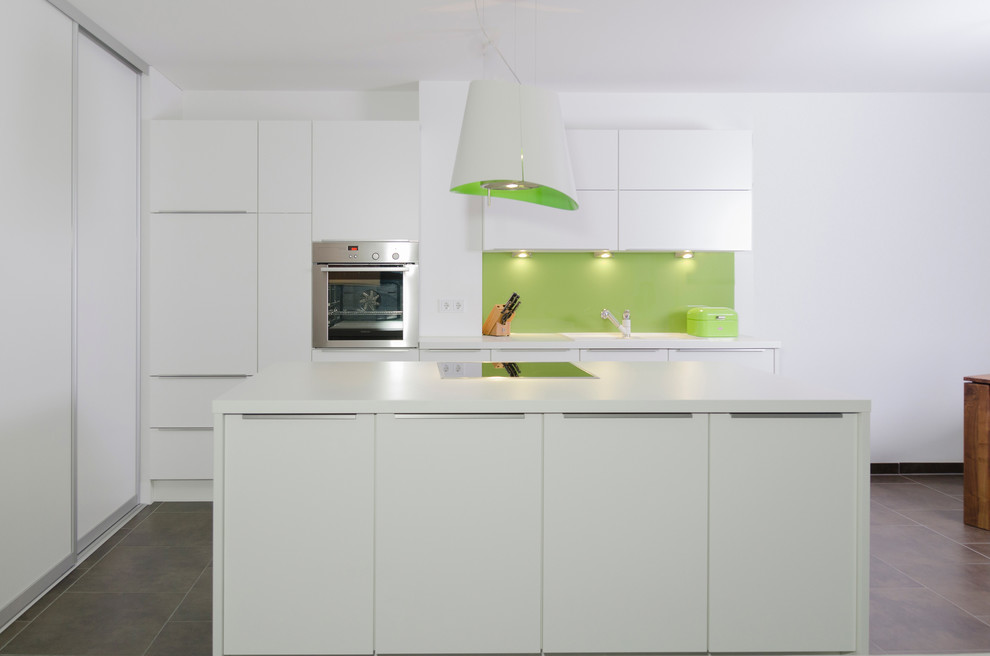 Inspiration for a large contemporary kitchen in Nuremberg with flat-panel cabinets, white cabinets, green splashback, stainless steel appliances, an island and a single-bowl sink.