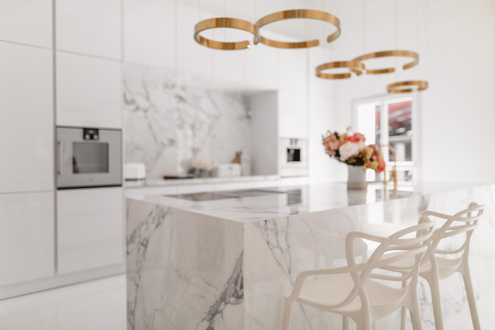 Eat-in kitchen - large contemporary galley white floor eat-in kitchen idea in Cologne with an integrated sink, flat-panel cabinets, white cabinets, marble countertops, white backsplash, ceramic backsplash, white appliances, an island and white countertops