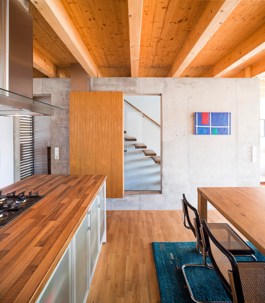 Moderne Wohnküche mit Arbeitsplatte aus Holz, braunem Holzboden, Kücheninsel, flächenbündigen Schrankfronten und grauen Schränken in Berlin