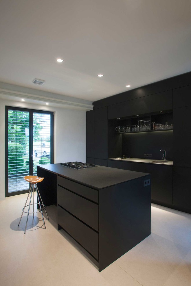 Photo of a medium sized contemporary single-wall kitchen/diner in Other with flat-panel cabinets, black cabinets, black splashback, integrated appliances, an island and a submerged sink.
