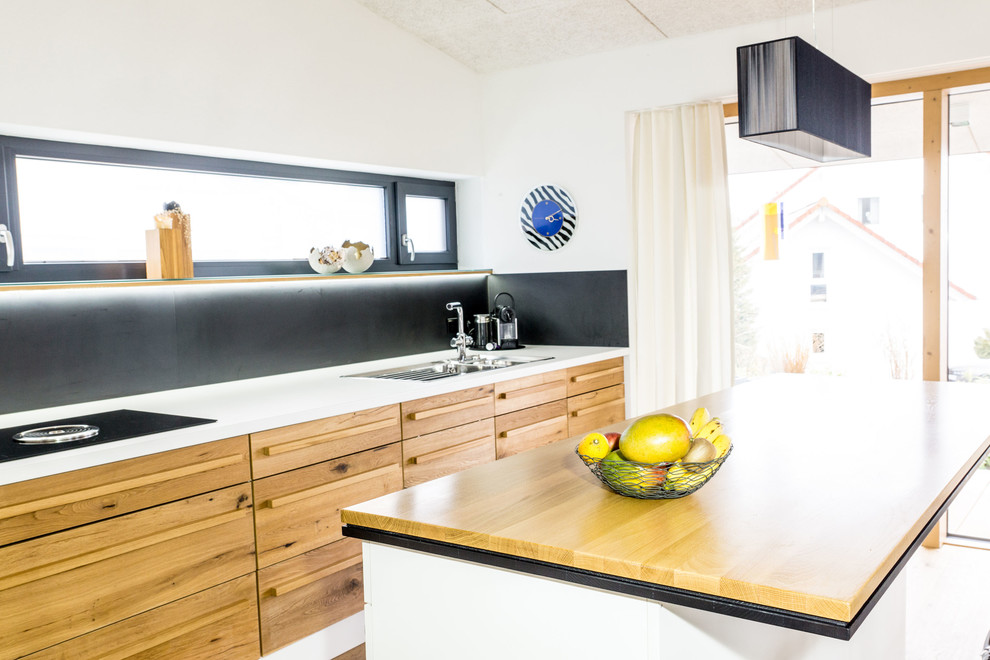 Идея дизайна: кухня-гостиная среднего размера в современном стиле с фасадами цвета дерева среднего тона, деревянной столешницей, черным фартуком и островом