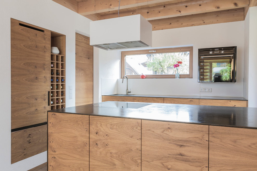 Cette image montre une petite cuisine ouverte parallèle chalet en bois brun avec un évier encastré, un placard à porte plane, un sol en bois brun et îlot.