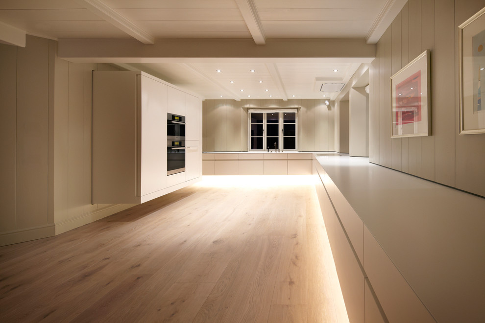 Foto de cocina contemporánea cerrada con suelo de madera clara, armarios con paneles lisos y puertas de armario blancas