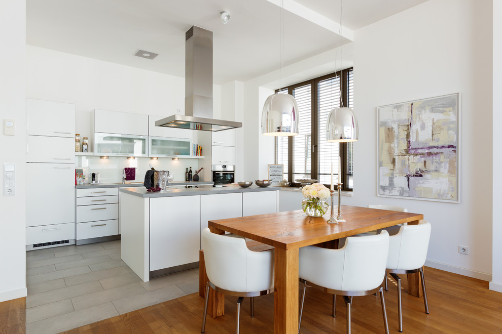 Medium sized contemporary open plan kitchen in Cologne with white cabinets, laminate countertops, stainless steel appliances, an island, grey worktops and cement flooring.
