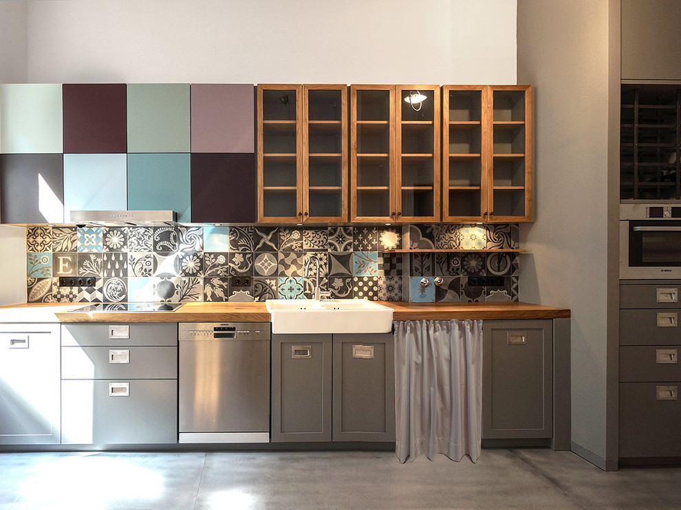 Foto på ett stort eklektiskt linjärt kök, med en rustik diskho, grå skåp, träbänkskiva, flerfärgad stänkskydd, rostfria vitvaror, betonggolv och stänkskydd i keramik