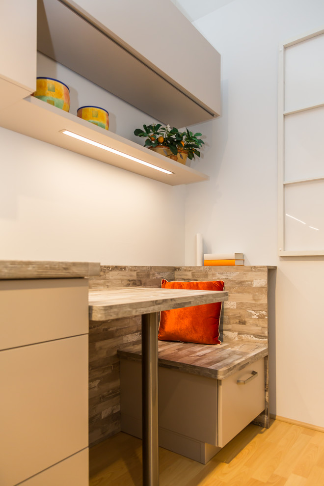 Kleine Moderne Küche mit flächenbündigen Schrankfronten, Arbeitsplatte aus Holz und braunem Holzboden in Dresden