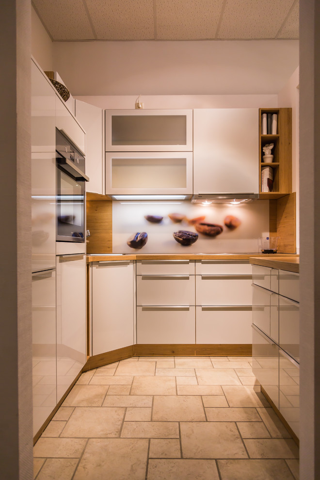 Kleine Moderne Küche in U-Form mit flächenbündigen Schrankfronten, Arbeitsplatte aus Holz, bunter Rückwand und Glasrückwand in Dresden