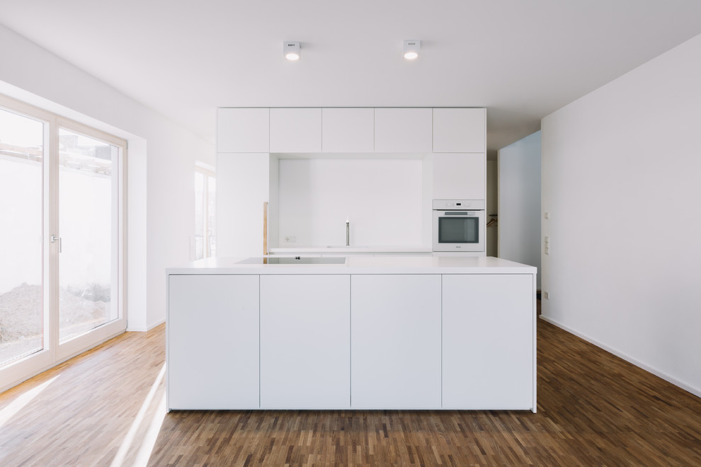 Idee per una cucina minimalista con ante bianche, top in acciaio inossidabile e pavimento in legno massello medio