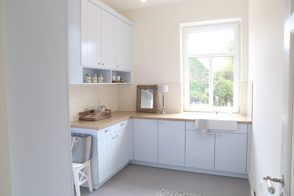 Exempel på ett mellanstort modernt kök, med blå skåp, träbänkskiva, grått golv, en integrerad diskho, släta luckor, vitt stänkskydd, stänkskydd i porslinskakel, rostfria vitvaror och cementgolv