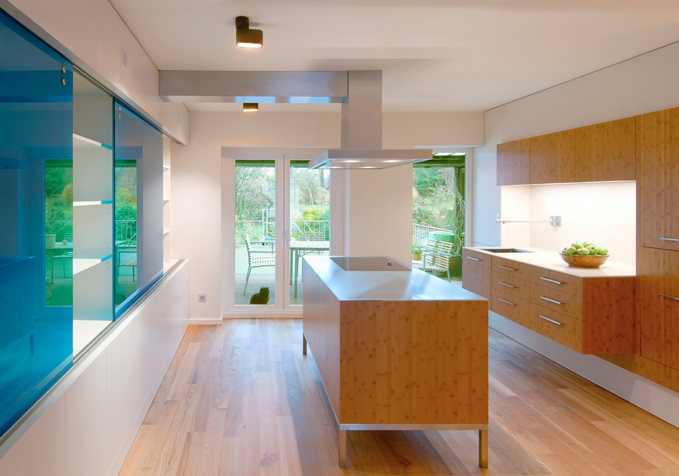 Immagine di una cucina design di medie dimensioni con lavello sottopiano, ante lisce, ante in legno scuro, pavimento in legno massello medio, top in acciaio inossidabile e elettrodomestici neri