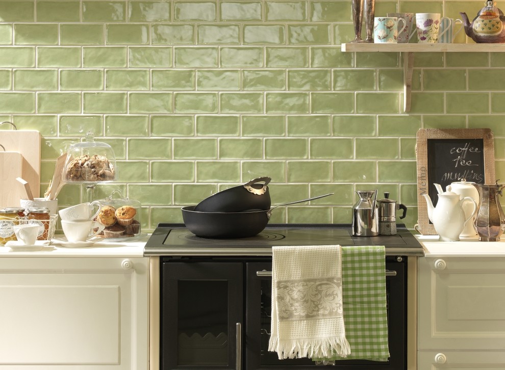 Cette image montre une cuisine linéaire rustique de taille moyenne avec un placard à porte affleurante, des portes de placard blanches, un plan de travail en quartz modifié, une crédence verte, une crédence en céramique et un électroménager noir.