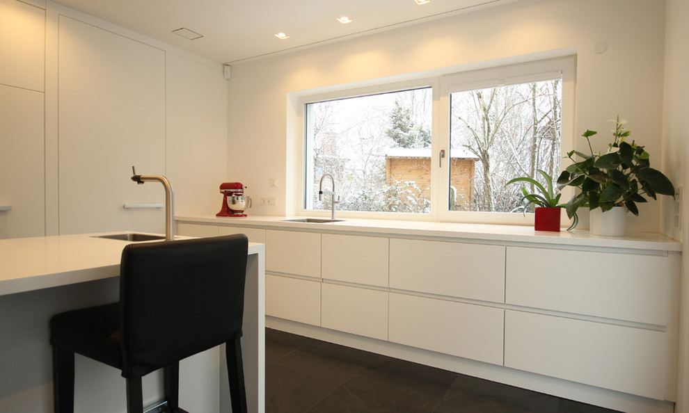 Esempio di una grande cucina design con ante bianche, elettrodomestici neri, paraspruzzi a finestra e top bianco