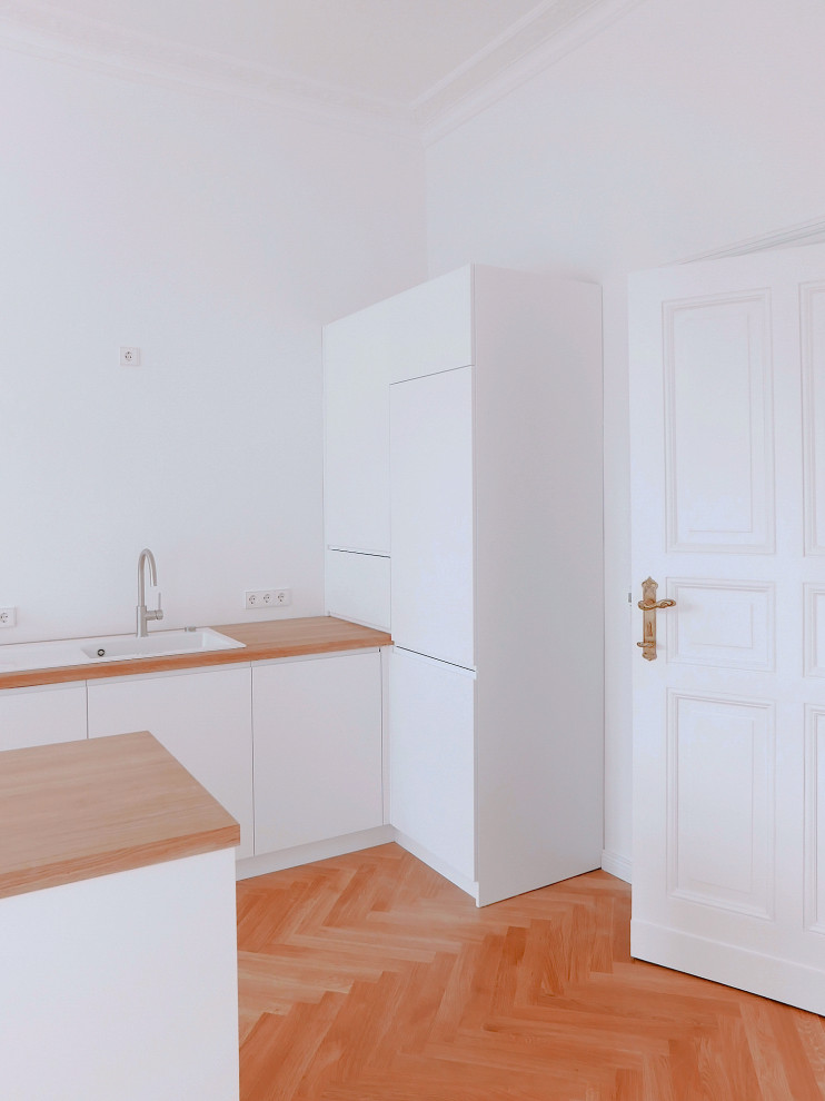 Idee per una cucina minimal con ante lisce, ante bianche, top in legno, pavimento in legno verniciato, pavimento marrone e top marrone