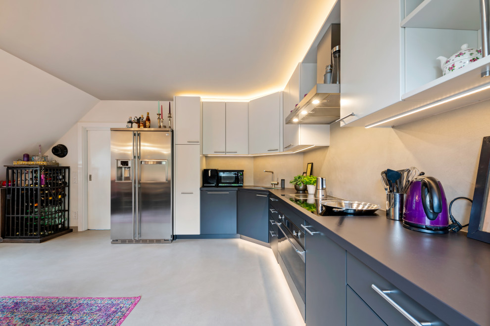 Große Moderne Wohnküche in L-Form mit Einbauwaschbecken, flächenbündigen Schrankfronten, Mineralwerkstoff-Arbeitsplatte, Küchenrückwand in Beige, beigem Boden und schwarzer Arbeitsplatte in München