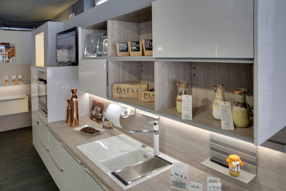 Einzeilige Moderne Küche mit Einbauwaschbecken, weißen Schränken, Küchenrückwand in Braun, Küchengeräten aus Edelstahl und braunem Boden in Stuttgart