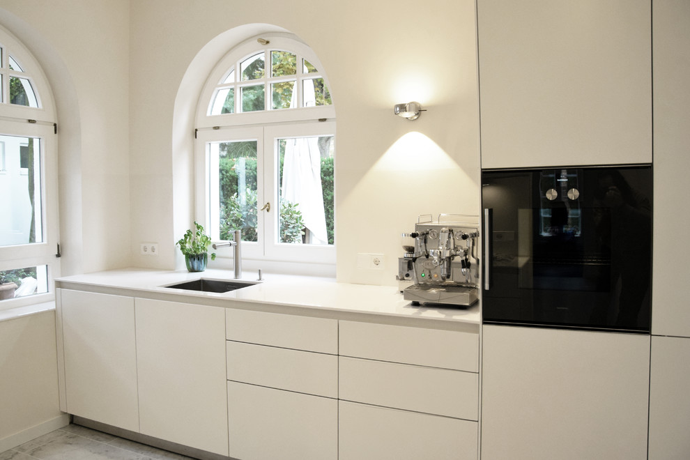 Moderne Küche ohne Insel mit Einbauwaschbecken, flächenbündigen Schrankfronten, weißen Schränken und Küchenrückwand in Weiß in Frankfurt am Main