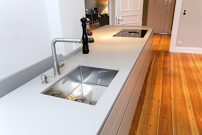Photo of an expansive contemporary galley open plan kitchen in Hamburg with a submerged sink, flat-panel cabinets, white cabinets, black appliances and light hardwood flooring.