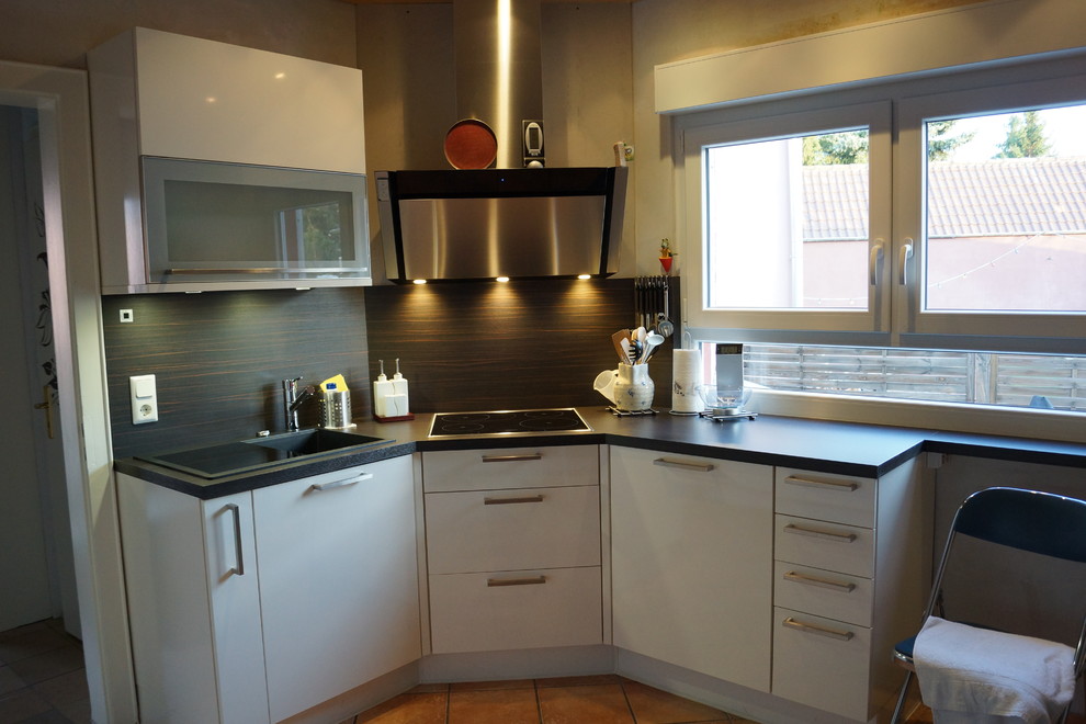 This is an example of a contemporary l-shaped open plan kitchen in Frankfurt with white cabinets and granite worktops.