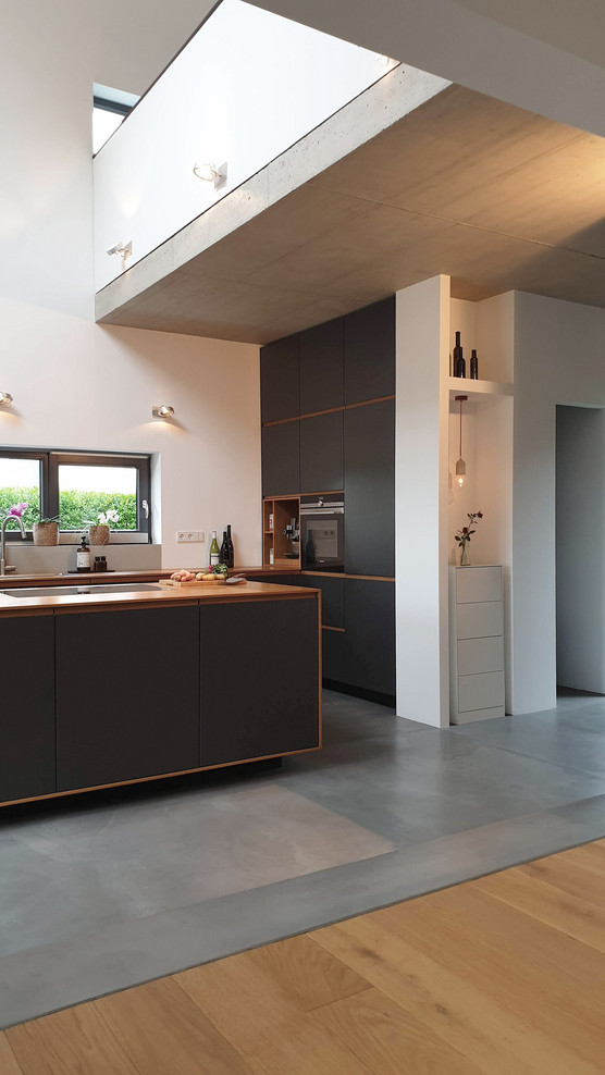 Nordische Küche mit schwarzen Schränken, Arbeitsplatte aus Holz und Kücheninsel in Köln