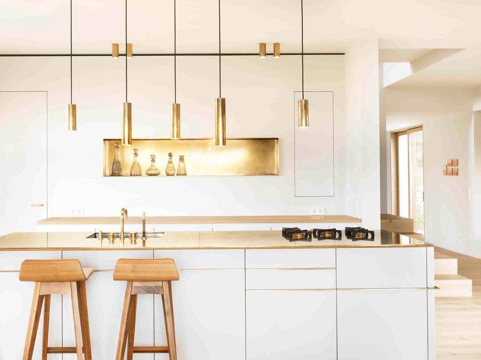 Immagine di una cucina contemporanea di medie dimensioni con lavello sottopiano, ante lisce, ante bianche e pavimento in legno massello medio