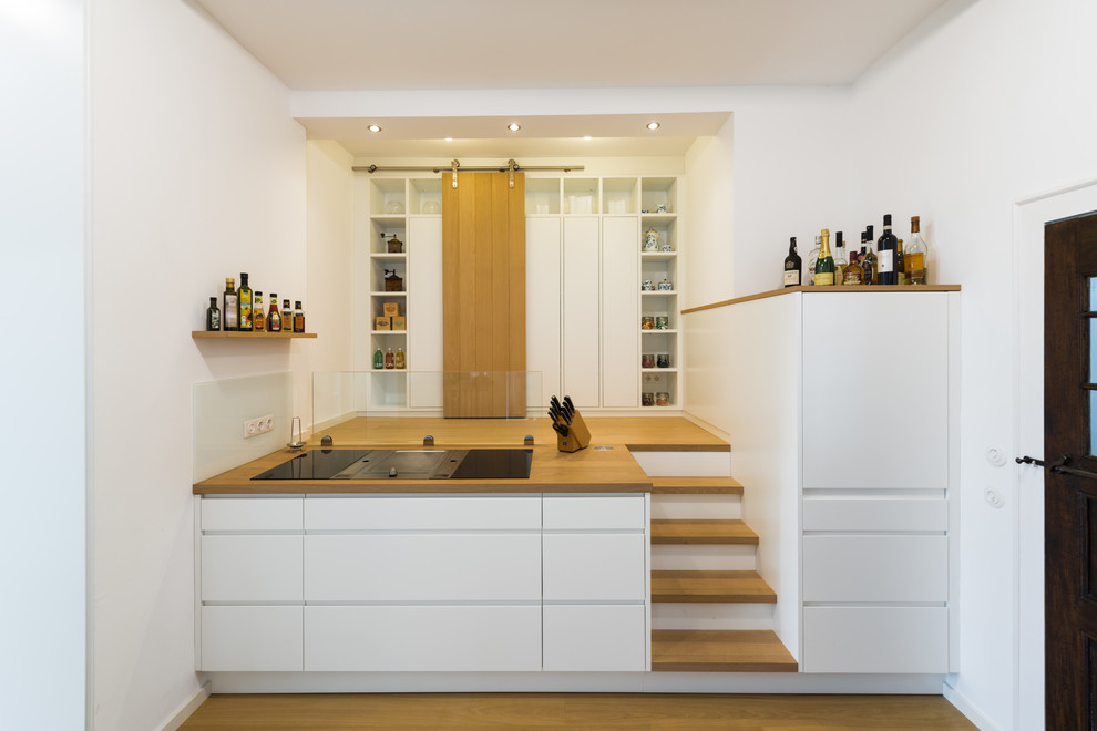 Inspiration for a medium sized modern single-wall enclosed kitchen in Other with a built-in sink, beaded cabinets, white cabinets, wood worktops, white splashback, glass sheet splashback, white appliances, light hardwood flooring, no island, beige floors and beige worktops.
