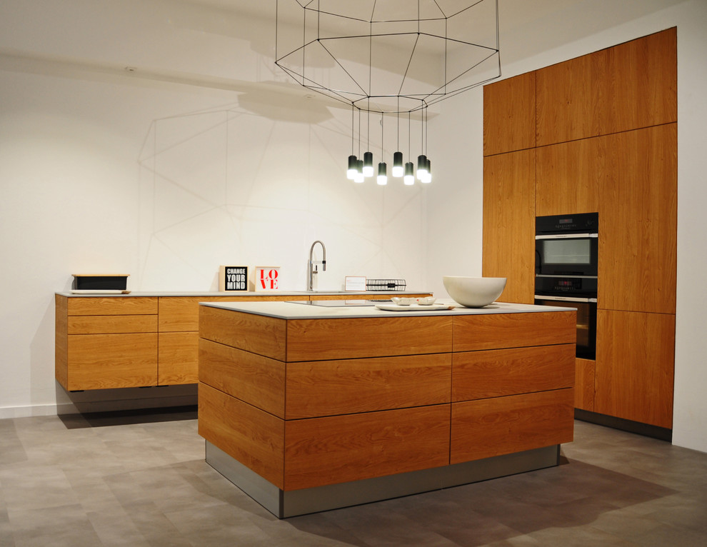 Cette photo montre une cuisine ouverte linéaire tendance en bois brun de taille moyenne avec un placard à porte plane, un électroménager noir, sol en béton ciré, îlot et un évier 1 bac.