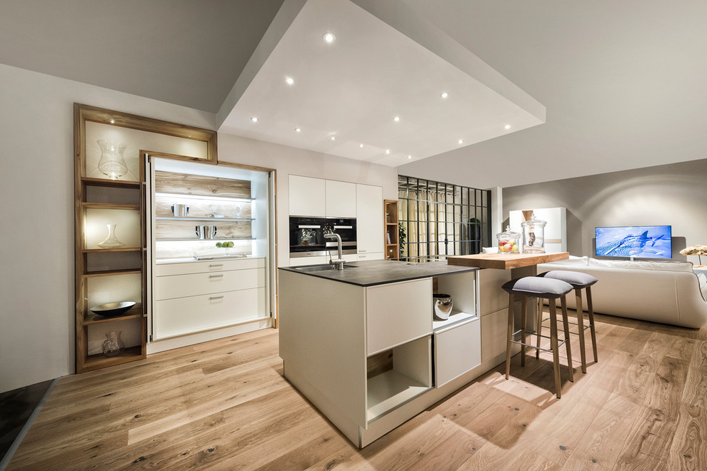Immagine di una cucina minimal di medie dimensioni con ante lisce, ante bianche, pavimento in legno massello medio e pavimento marrone