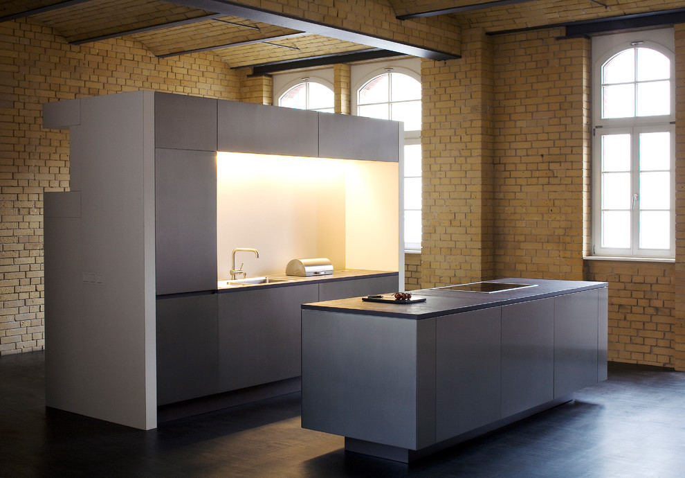 Offene, Zweizeilige Industrial Küche mit grauen Schränken, Kücheninsel, schwarzen Elektrogeräten und Linoleum in Berlin
