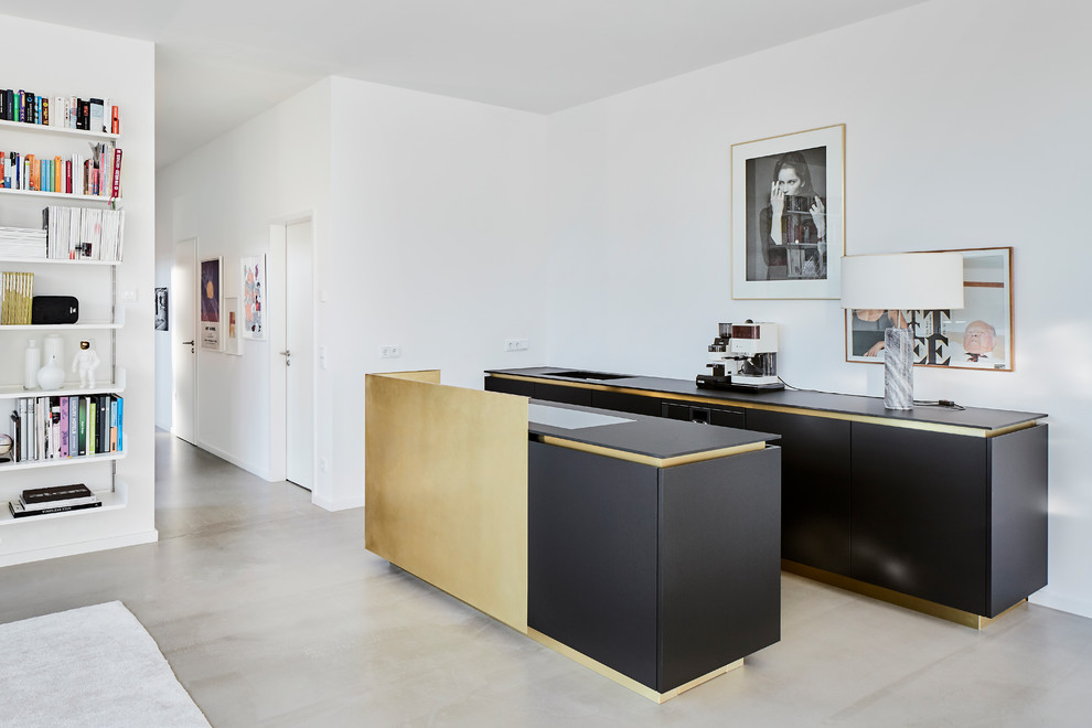 Offene, Zweizeilige, Kleine Moderne Küche mit flächenbündigen Schrankfronten, schwarzen Schränken, Kücheninsel, grauem Boden, schwarzer Arbeitsplatte und Küchenrückwand in Weiß in Köln