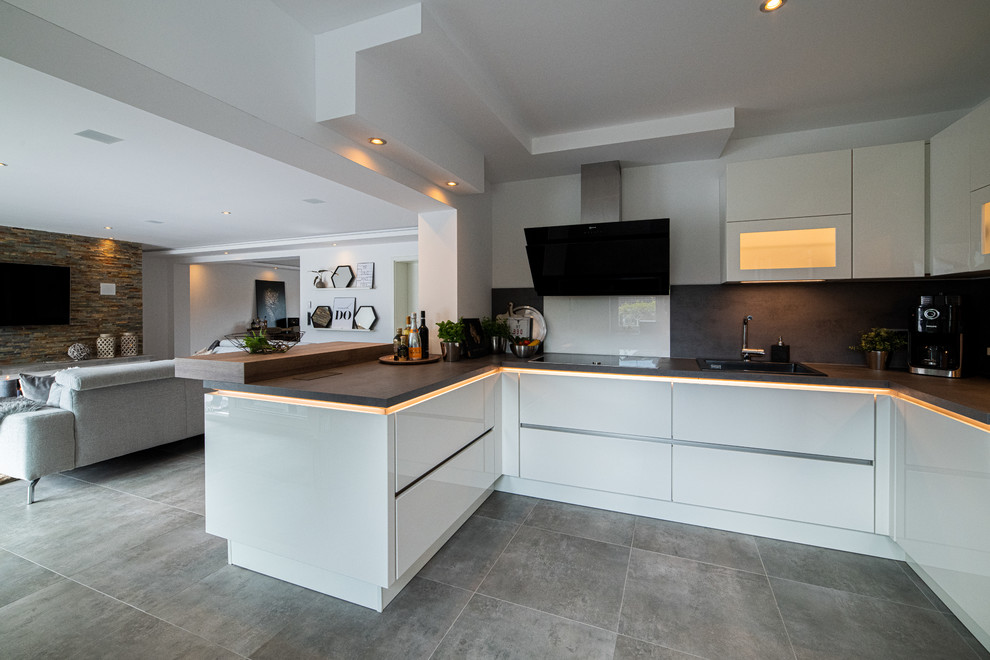 Modern inredning av ett mellanstort u-kök, med klinkergolv i keramik, grått golv, en enkel diskho, släta luckor, vita skåp, träbänkskiva, brunt stänkskydd, stänkskydd i trä, rostfria vitvaror och en halv köksö