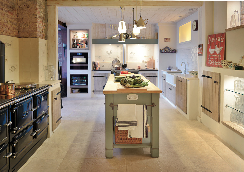 Inspiration for a medium sized rural l-shaped open plan kitchen in Dusseldorf with a belfast sink, raised-panel cabinets, light wood cabinets, limestone worktops, black appliances, limestone flooring, an island and beige floors.