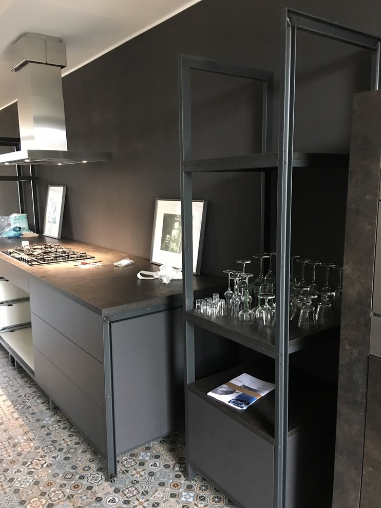 ライプツィヒにある中くらいなインダストリアルスタイルのおしゃれなキッチン (ダブルシンク、シルバーの調理設備、磁器タイルの床) の写真