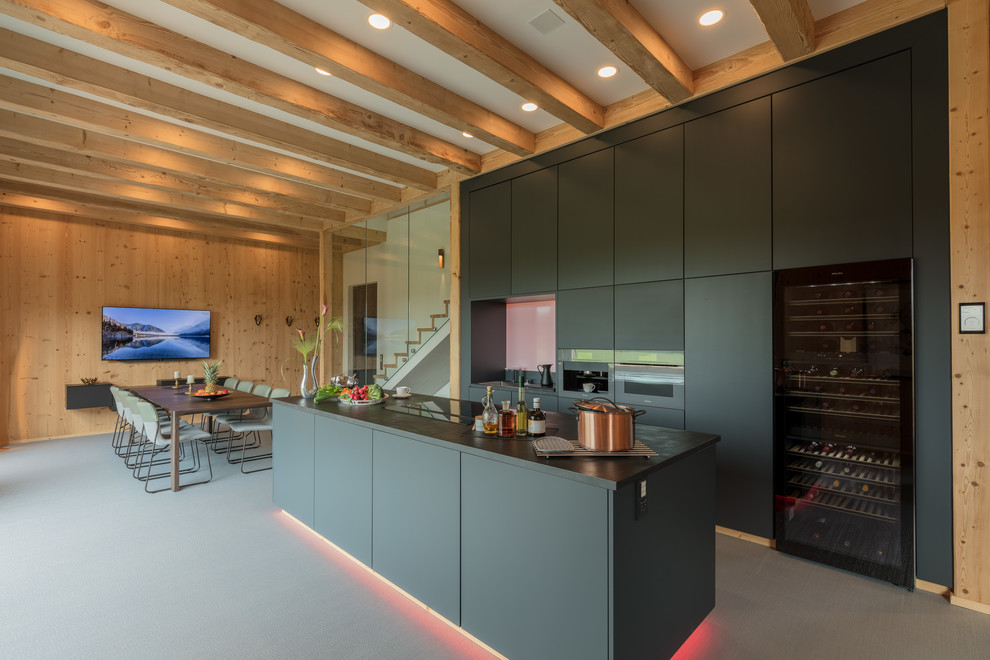 Design ideas for a large contemporary galley open plan kitchen in Stuttgart with flat-panel cabinets, black cabinets, an island, grey floors, black worktops and black appliances.