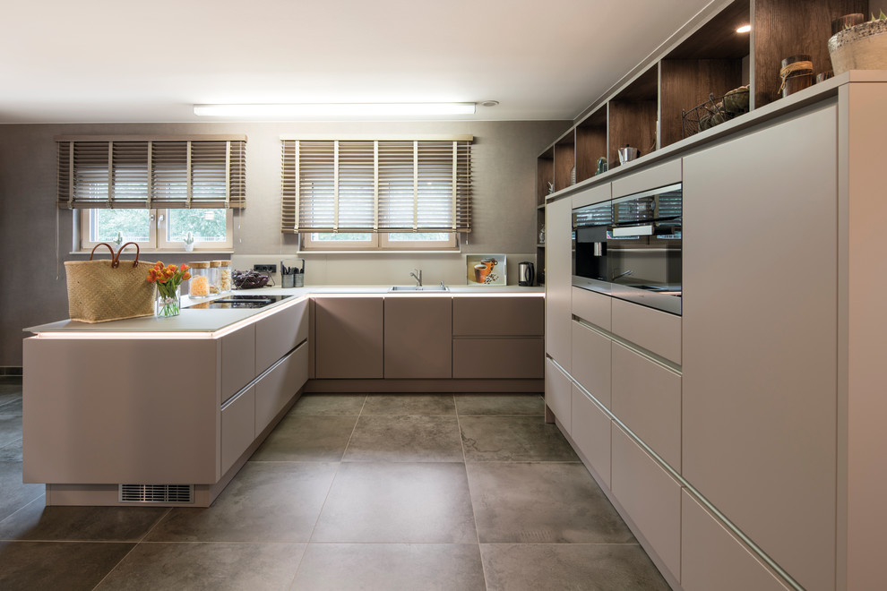 Medium sized contemporary u-shaped open plan kitchen in Other with a breakfast bar, brown floors, beige worktops, a built-in sink, flat-panel cabinets, brown cabinets and black appliances.