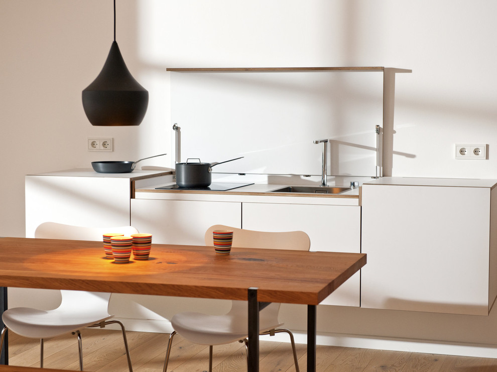 Bild på ett litet minimalistiskt kök och matrum, med vita skåp