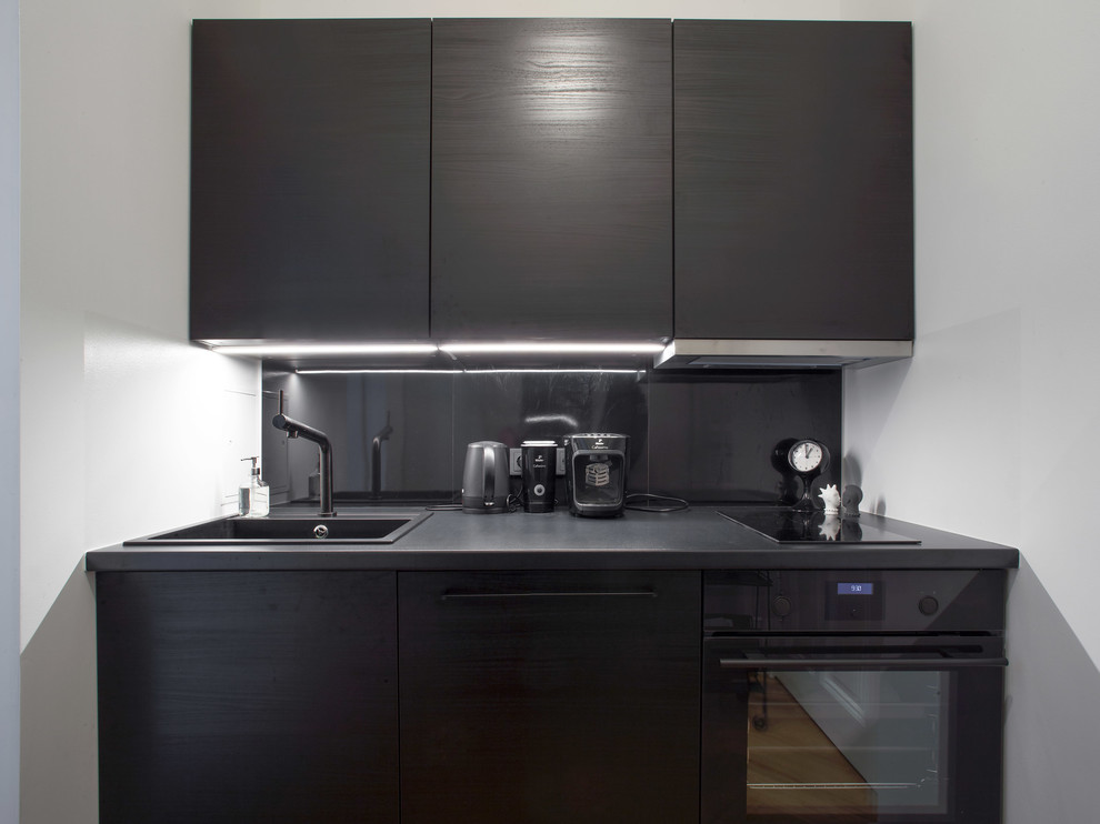 Idéer för avskilda, små funkis linjära kök, med en integrerad diskho, luckor med lamellpanel, svarta skåp, laminatbänkskiva, svart stänkskydd, stänkskydd i metallkakel, svarta vitvaror, mellanmörkt trägolv och brunt golv