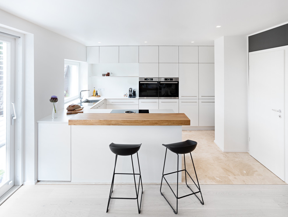 Bild på ett mellanstort funkis kök, med släta luckor, vita skåp, vitt stänkskydd, rostfria vitvaror, en halv köksö, en enkel diskho, laminatbänkskiva och stänkskydd i trä
