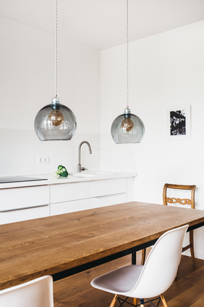 Идея дизайна: огромная прямая кухня в скандинавском стиле с обеденным столом, плоскими фасадами, белыми фасадами, деревянной столешницей, белым фартуком и белой столешницей без острова